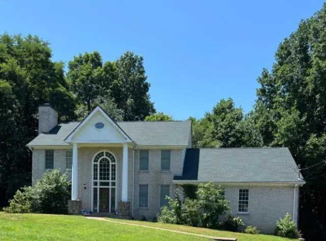 Two-story brick house with a gray shingle roof and a columned entry, Nashville